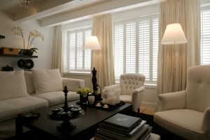 Full height plantation shutters installed across a wide living room window